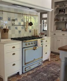 a kitchen with an old fashioned stove and oven in the center, surrounded by white cabinets