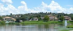 a lake with houses in the background and trees around it, surrounded by lush green grass