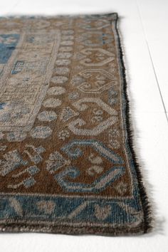 an old rug is laying on the floor with white tiles in the background and light blue accents