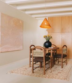 a dining room table with chairs and a vase on it