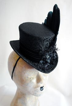 This elegant gothic mini top hat is covered with wonderful black brocade. It is luxuriously decorated with a unique hand-crafted faux raven wing along with curled ostrich spray and black blossoms with crystal details. IMPORTANT NOTE: The fabric seen in the pictures is permanently SOLD OUT! The hat you'll receive will be covered in the brocade seen in the LAST PICTURE. Measurements : height 4 inches( 10 cm ) front to back 9 inches ( 22 cm ) side to side 7.5 inches ( 19 cm ) This mini top hat is f Gothic Black Mini Hats For Halloween, Black Top Hat For Costume, Fitted Top Hat With Curved Brim For Costume, Black Fitted Top Hat For Costume, Fitted Black Top Hat For Costume, Steampunk Top Hat For Halloween Cosplay, Gothic Black Top Hat For Costume Party, Black Gothic Top Hat For Costume Party, Fitted Witchy Hat For Halloween