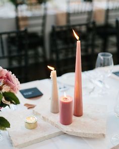 two candles are sitting on a table with flowers