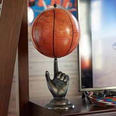 a basketball sitting on top of a wooden desk next to a computer monitor and keyboard