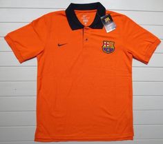 an orange polo shirt with black collar and two patches on the chest, sitting against a white wall