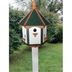 a white and green bird house sitting in the grass