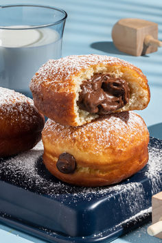 two chocolate filled doughnuts on a blue plate next to a glass of milk