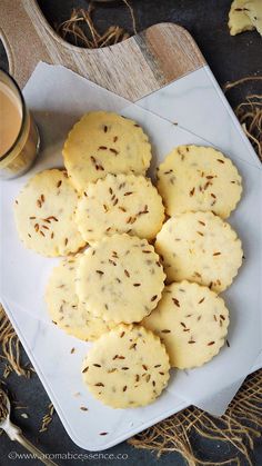 some cookies are on a plate next to a cup of coffee and a spoon in the background