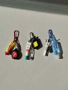 three different key chains with various items attached to them on a table, one has a lighter and the other is an empty bottle