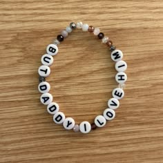 a beaded bracelet with words written in white and brown beads on a wooden surface