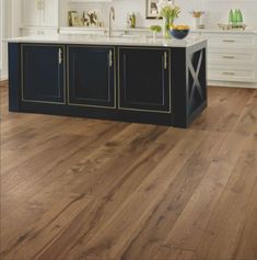 a large kitchen with wooden floors and white cabinets