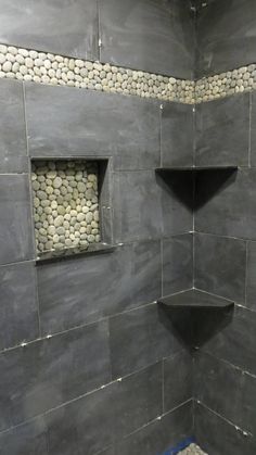 a walk in shower sitting next to a tiled wall with two niches on each side