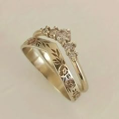 two gold wedding rings with flowers and leaves on each band, set against a white background