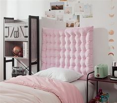 a bedroom with a pink headboard and white sheets on the bed, next to a small table