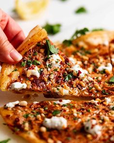 a person holding a slice of pizza with cheese and spinach on it, being lifted from the plate