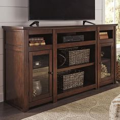 a flat screen tv sitting on top of a wooden entertainment center next to a window