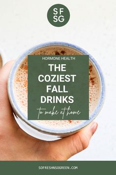 a hand holding a cup of coffee with the words, the coziest fall drinks to make at home