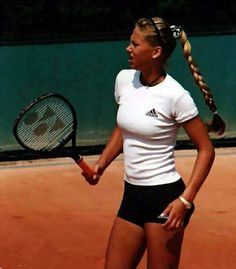 a woman holding a tennis racquet on top of a tennis court