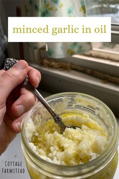 a hand holding a spoon in a glass jar filled with cottage cheese and garlic oil