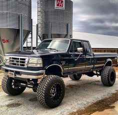 a large black truck parked in front of some silos