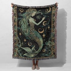 a woman standing in front of a tapestry with a mermaid on it's back