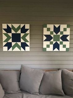 two quilts are hanging on the wall above a couch