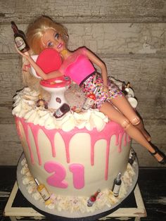 a barbie doll sitting on top of a cake with pink icing and sprinkles