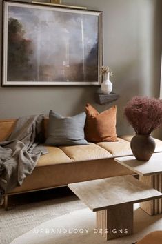 a living room filled with furniture and a painting hanging on the wall above it's windows