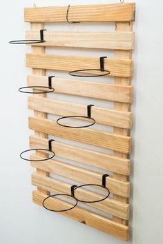 a wooden rack with metal rings hanging from it's sides on a white wall