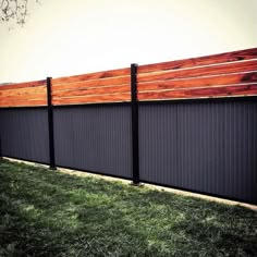 a wooden fence with black slats in the grass