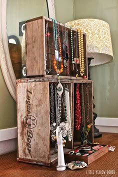 an old wooden box with jewelry hanging on it and a lamp in the corner next to it