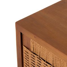 a wooden table with wicker baskets on the top and bottom drawer, against a white background