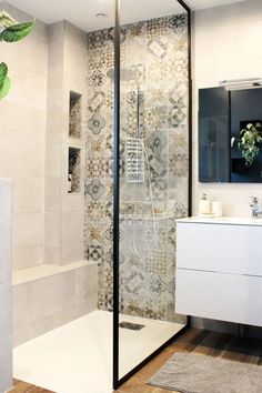 a bathroom with a walk in shower next to a white sink and mirror on the wall