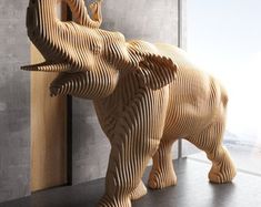 an elephant sculpture made out of wood on a table next to a wall and window