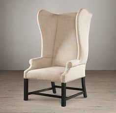 a white upholstered chair with wooden legs and nail polishing on the back