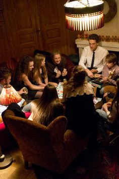 a group of people sitting around each other in a living room next to a fire place