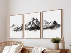 three black and white paintings hanging on the wall above a wicker chair in a room