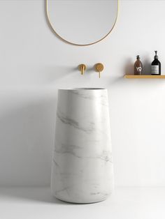 a white marble pedestal sink next to a round mirror