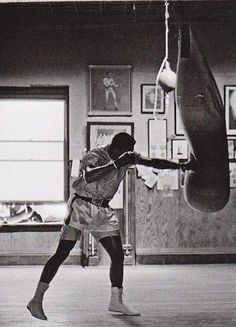 an old photo of a man hitting a punching bag