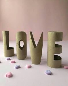 the word love made out of toilet paper surrounded by small candies on a table