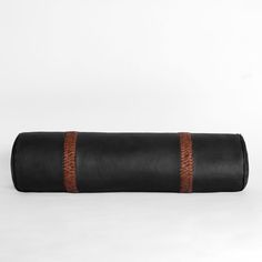 a black leather yoga mat with brown stitching on the top and bottom, rolled up in half