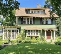 a large green house sitting in the middle of a lush green yard with lots of trees