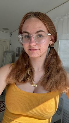 a woman with glasses on taking a selfie in front of the camera while wearing a yellow tank top