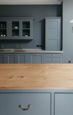 a kitchen with gray cabinets and wooden counter tops