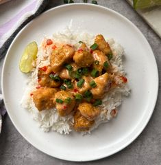 a white plate topped with rice and meat next to a slice of lime wedges