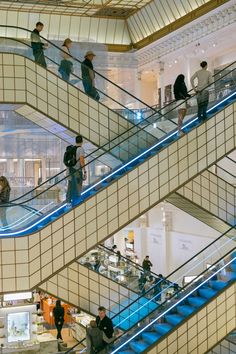 people are walking up and down an escalator in a shopping mall with blue railings