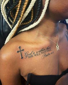 the back of a woman's shoulder with a cross and bible tattoo on it