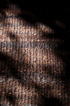 the shadow of a person's head on a brown and black carpeted surface