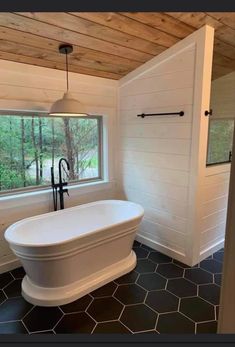 a white bath tub sitting under a window in a bathroom