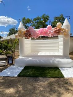 an inflatable bed is set up on the lawn with balloons and streamers