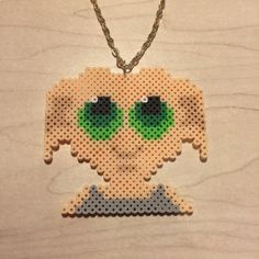 a cross stitch necklace with green eyes on it